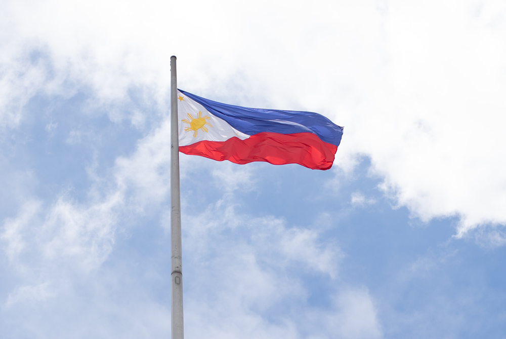 Philippine flag on top of a pole, waving in the wind