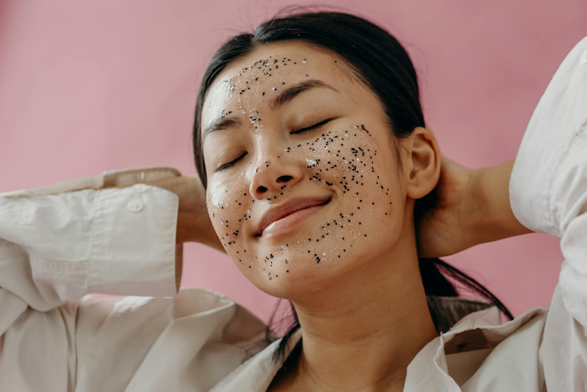 A smiling woman with exfoliating scrub on her face